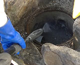 汚水マスの内部の汚れを、高圧洗浄機の水で削ぎ落としている写真